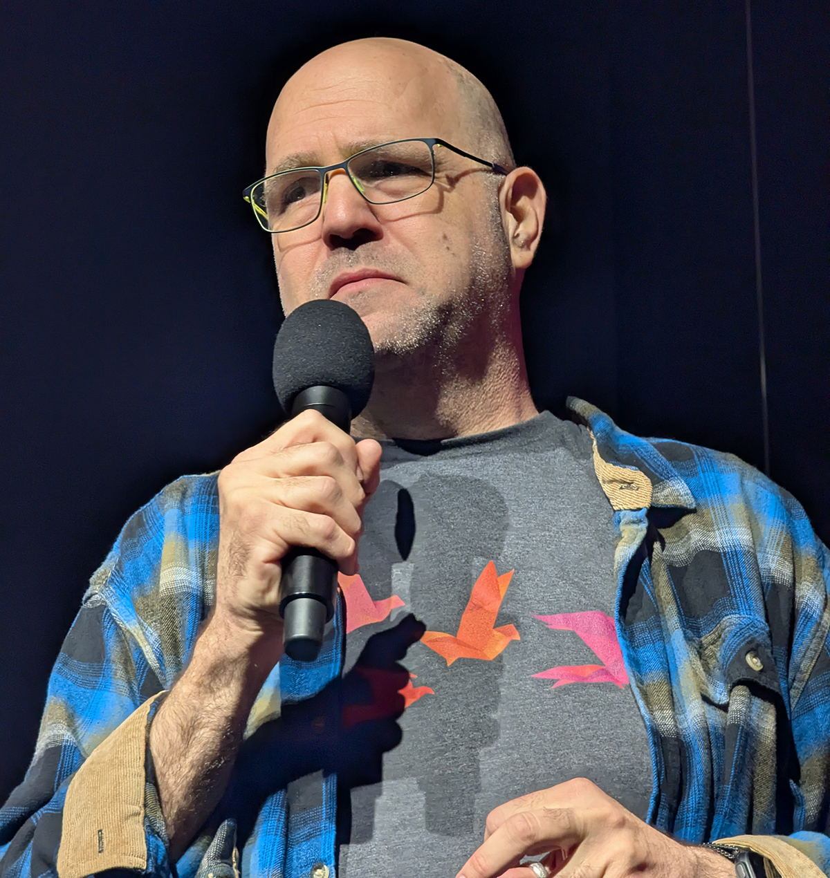 Photograph of Gadi Evron, founder and CEO of Knostic AI and CISO-in-Residence for AI at the Cloud Security Alliance, speaking into a handheld microphone at Zenity's Agentic AI Security Summit, illustrating his call for every enterprise to set up agentic-led VulnOps to keep pace with the threats of the post-AI age. Source: HFS Research, 2026.
