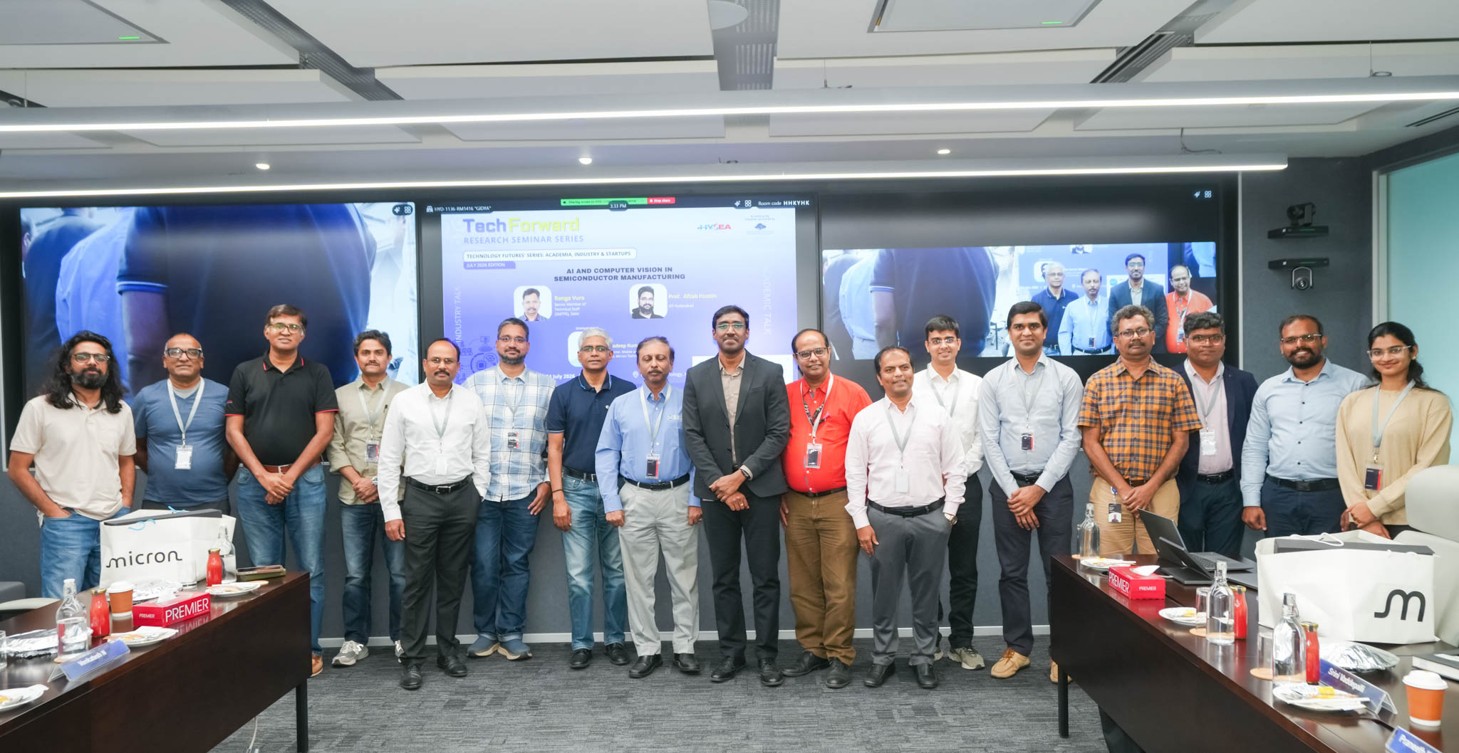 Group photograph of 18 ER&D GCC leaders and academics standing in a Micron Innovation Center conference room in front of a display screen for the TechForward Research Seminar Series session titled